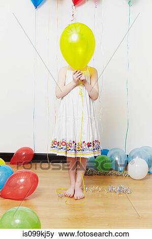 Girl holding balloon in front of face View Large Photo Image Stock Photo - Girl holding balloon in front of face. Fotosearch