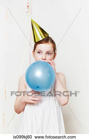 Girl in party hat, blowing up balloon View Large Photo Image Stock Image - Girl in party hat, blowing up balloon. Fotosearch