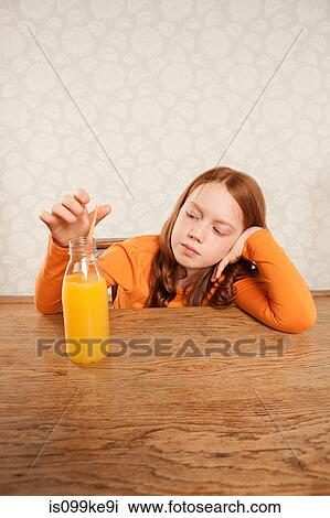 Girl looking at bottle of orange juice View Large Photo Image Stock Image - Girl looking at bottle of orange juice. Fotosearch