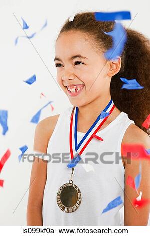 Stock Image - Girl wearing medal with ticker tape falling. Fotosearch