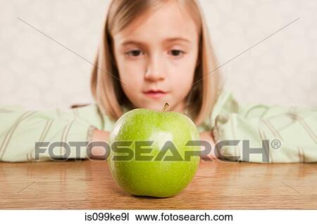 Little girl looking at an apple View Large Photo Image Stock Image - Little girl looking at an apple. Fotosearch