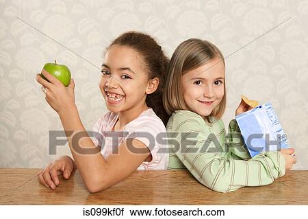One girl with an apple, one girl with a packet of crisps View Large Photo Image Stock Image - One girl with an apple, one girl with a packet of crisps. Fotosearch