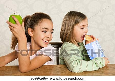 One girl with an apple, one girl with a packet of crisps View Large Photo Image Stock Photo - One girl with an apple, one girl with a packet of crisps. Fotosearch