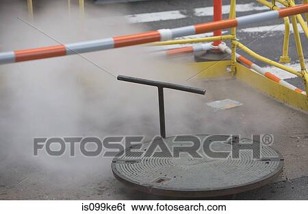 Stock Photograph - Roadworks with manhole cover and steam. Fotosearch