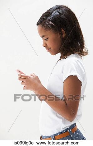 Stock Image - African American girl using cellphone, studio shot. Fotosearch