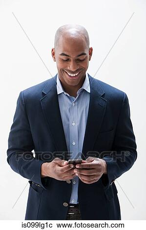 Stock Image - African American man using cellphone, studio shot. Fotosearch