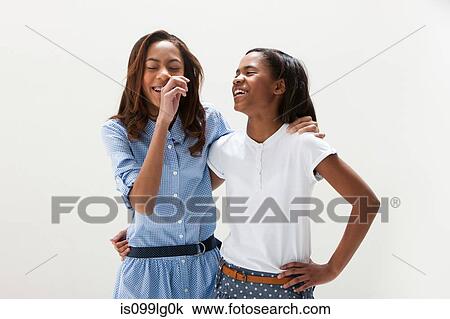 Stock Image - African American sisters standing together, studio shot. Fotosearch