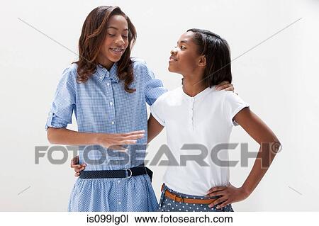 Stock Image - African American sisters standing together, studio shot. Fotosearch