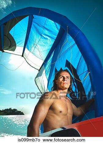 Athletic man carrying kiteboarding equipment View Large Photo Image Picture - Athletic man carrying kiteboarding equipment. Fotosearch