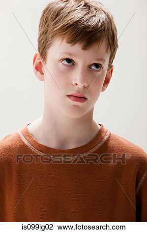 Stock Image - Boy in brown sweater rolling eyes, studio shot. Fotosearch