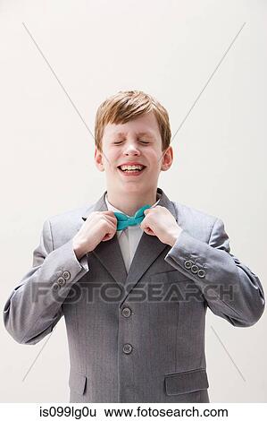 Boy wearing grey suit adjusting bow tie, studio shot View Large Photo Image Stock Photograph - Boy wearing grey suit adjusting bow tie, studio shot. Fotosearch