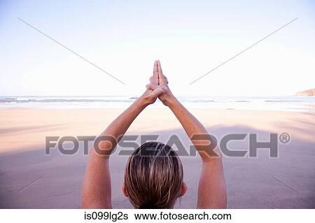 Stock Photograph - Close up of hands of woman in tree yoga pose on beach. Fotosearch