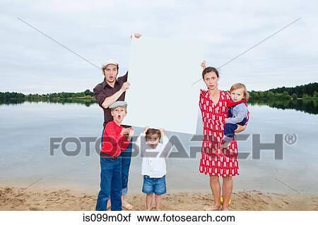 Stock Image - Family by lake, holding a blank sign. Fotosearch