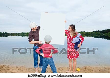 Stock Image - Family by lake, looking at a blank sign. Fotosearch