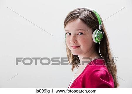Stock Image - Girl in red wearing headphones, studio shot. Fotosearch