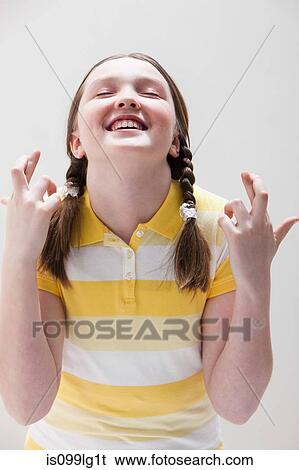 Stock Photograph - Girl with fingers crossed, studio shot. Fotosearch