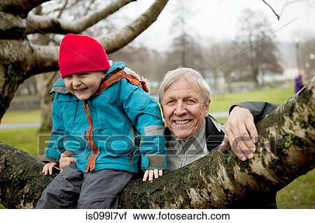 Granfather and boy sitting on tree branch, smiling View Large Photo Image Stock Image - Granfather and boy sitting on tree branch, smiling. Fotosearch