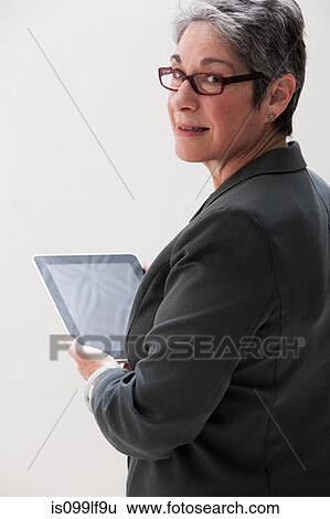 Stock Photograph - Mature businesswoman using digital tablet, studio shot. Fotosearch