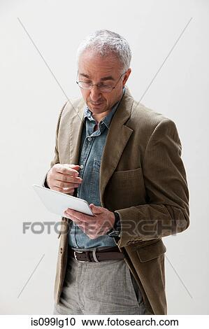 Stock Image - Mature man looking at digital tablet, studio shot. Fotosearch