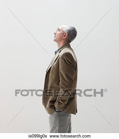 Stock Photo - Mature man with hands in pocket looking up, studio shot. Fotosearch