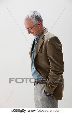 Stock Photo - Mature man with hands in pocket looking down, studio shot. Fotosearch