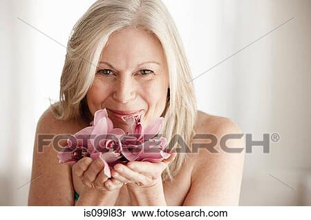 Stock Photography - Mature woman holding flower, portrait. Fotosearch