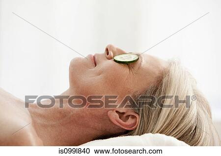 Mature woman relaxing with cucumber slices over eyes View Large Photo Image Stock Image - Mature woman relaxing with cucumber slices over eyes. Fotosearch