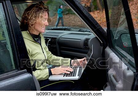 Stock Photo - Mature woman using laptop in car. Fotosearch