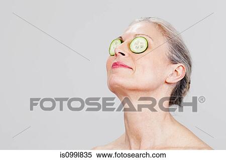 Mature woman wearing cucumber slices over eyes, smiling View Large Photo Image Stock Photography - Mature woman wearing cucumber slices over eyes, smiling. Fotosearch