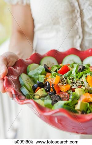 Stock Image - Mid adult woman holding salad bowl. Fotosearch