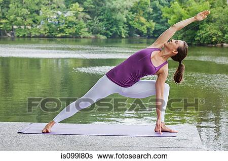Mid adult woman performing yoga by river View Large Photo Image Stock Photograph - Mid adult woman performing yoga by river. Fotosearch