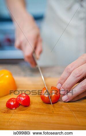Mid adult woman slicing cherry tomatoes View Large Photo Image Stock Image - Mid adult woman slicing cherry tomatoes. Fotosearch