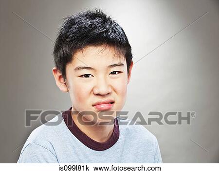 Stock Image - Portrait of grimacing young Asian teenage boy. Fotosearch