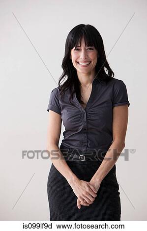 Stock Image - Portrait of mature woman smiling, studio shot. Fotosearch