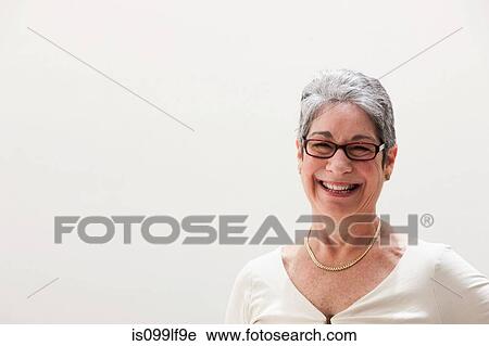 Stock Image - Portrait of mature woman smiling, studio shot. Fotosearch