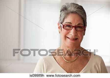 Stock Image - Portrait of mature woman smiling, studio shot. Fotosearch