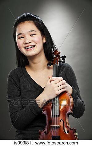 Portrait of young Asian teenage girl holding violin, smiling View Large Photo Image Stock Photograph - Portrait of young Asian teenage girl holding violin, smiling. Fotosearch
