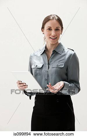 Picture - Portrait of young businesswoman smiling and using digital tablet, studio shot. Fotosearch