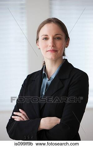 Stock Image - Portrait of young businesswoman smiling, studio shot. Fotosearch