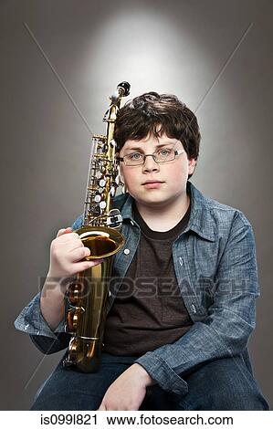 Portrait of young teenage boy holding saxophone View Large Photo Image Stock Image - Portrait of young teenage boy holding saxophone. Fotosearch