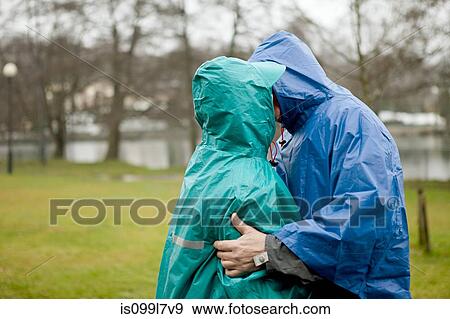 Senior couple in waterproof clothing kissing in park View Large Photo Image Stock Photo - Senior couple in waterproof clothing kissing in park. Fotosearch