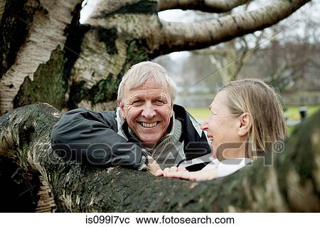 Senior couple leaning against tree, smiling View Large Photo Image Stock Image - Senior couple leaning against tree, smiling. Fotosearch