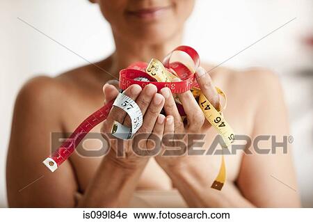 Stock Image - Senior woman holding measuring tapes in hands. Fotosearch