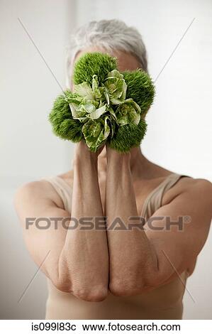 Senior woman holding plant in front of face View Large Photo Image Stock Image - Senior woman holding plant in front of face. Fotosearch