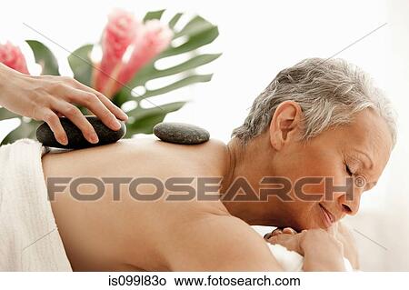Picture - Senior woman receiving stone therapy. Fotosearch