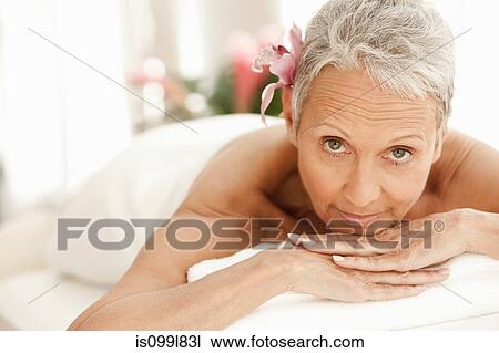 Stock Image - Senior woman relaxing on massage table, portrait. Fotosearch