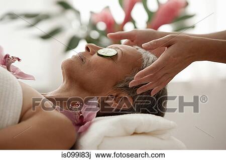Senior woman wearing cucumber slices and relaxing on massage table View Large Photo Image Stock Image - Senior woman wearing cucumber slices and relaxing on massage table. Fotosearch