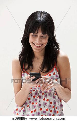 Stock Photo - Smiling mature woman using cellphone, studio shot. Fotosearch