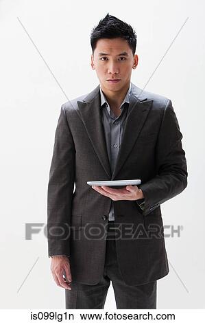 Picture - Young Asian businessman holding digital tablet, studio shot. Fotosearch