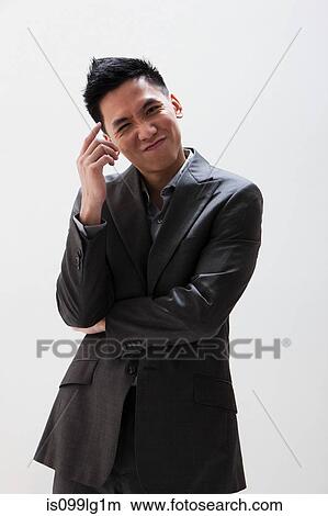 Young Asian businessman scratching head, studio shot View Large Photo Image Picture - Young Asian businessman scratching head, studio shot. Fotosearch